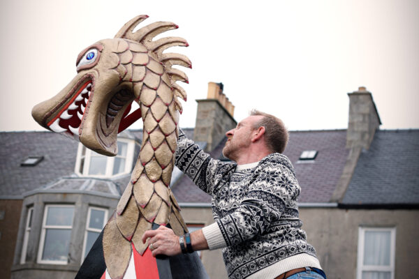 A man in the street with a dragon figurehead