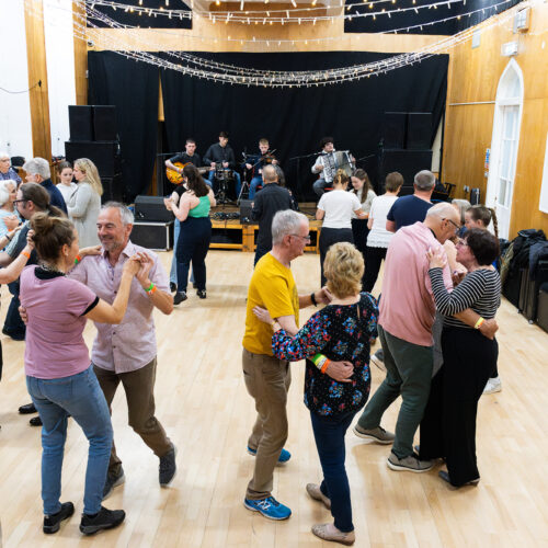 People dancing in couples in a hall with a live band