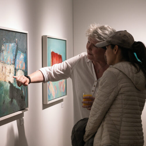 Two people in an art gallery looking at a painting