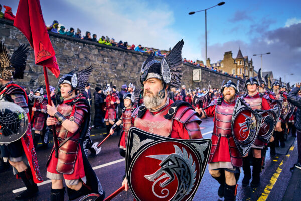 A parade of people dressed as Vikings walking down a street
